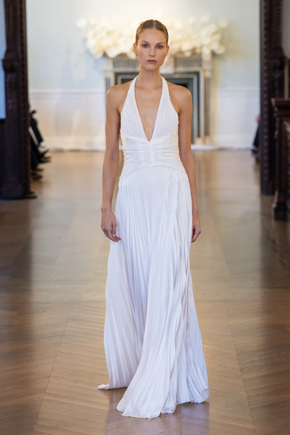 2703 - LEE PETRA GREBENAU - A deep V-neck gown with a cinched, ruched waist and a cascading, pleated skirt.