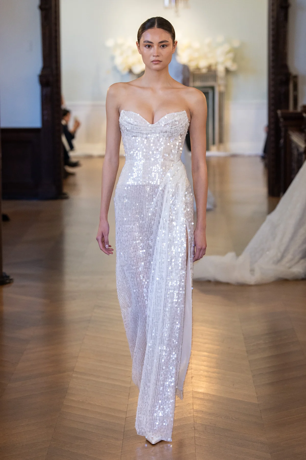 2710 - LEE PETRA GREBENAU - A shimmering, fitted gown fully covered in a layer of sequins and a gentle drape at the waist that cascades through the skirt.
