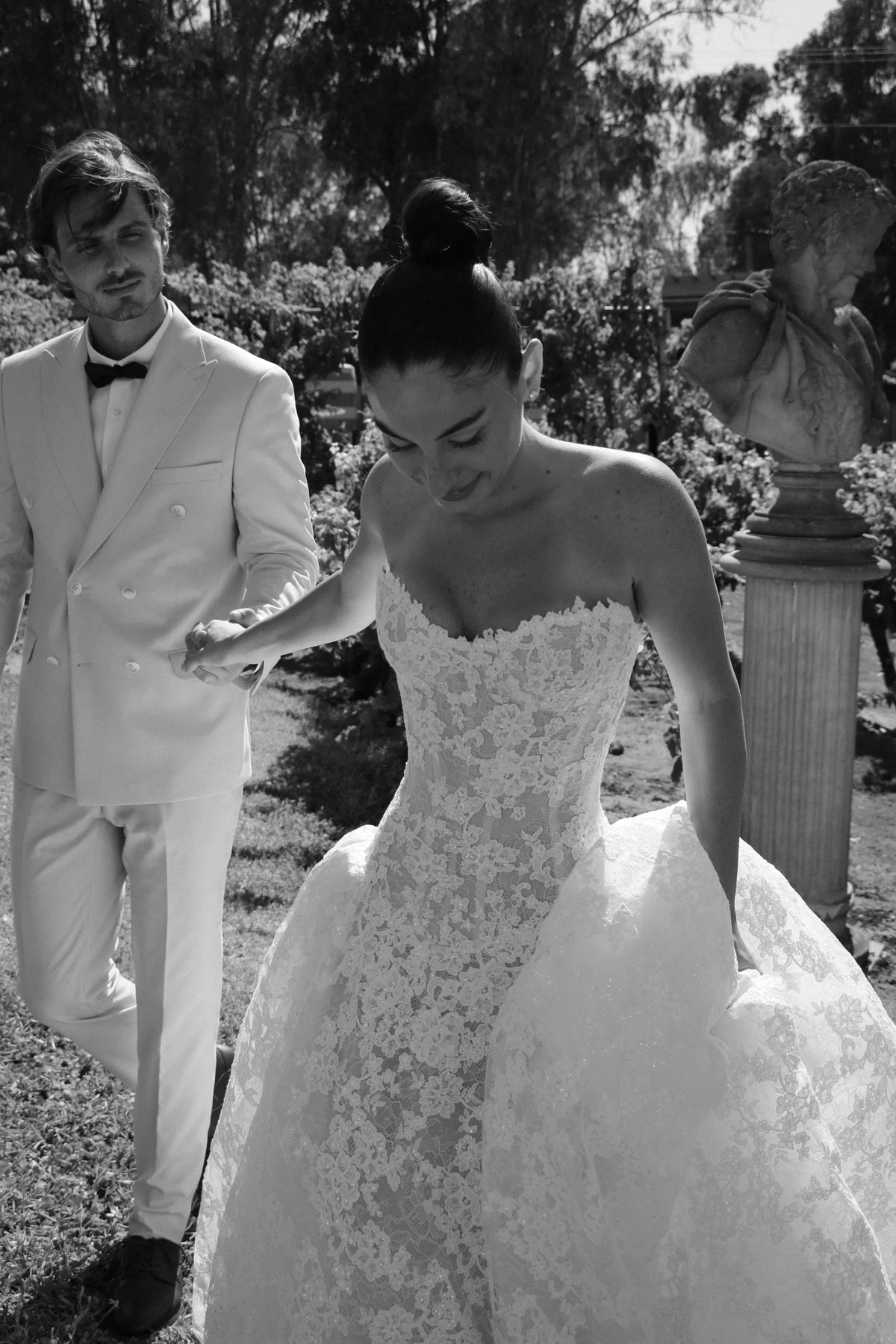 Bride and groom walking in black and white — Lee Petra Grebenau Talisman lace ball gown