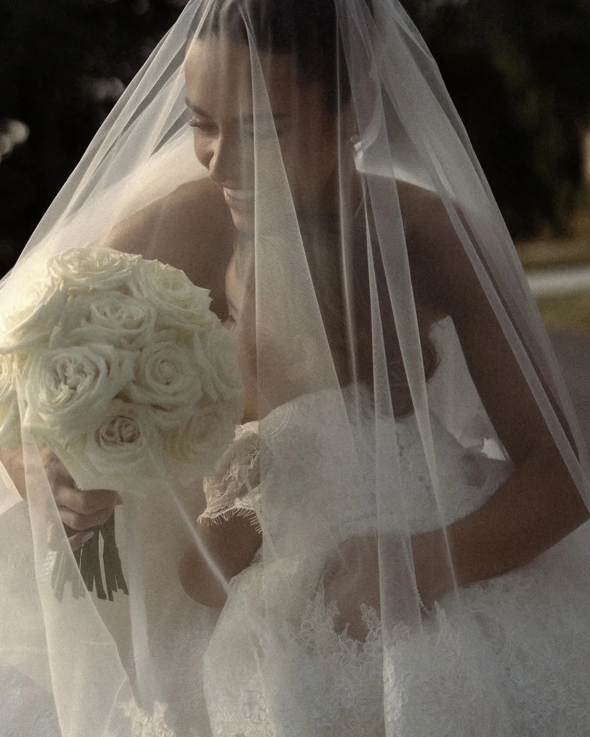 Danielle beneath her veil holding a white rose bouquet