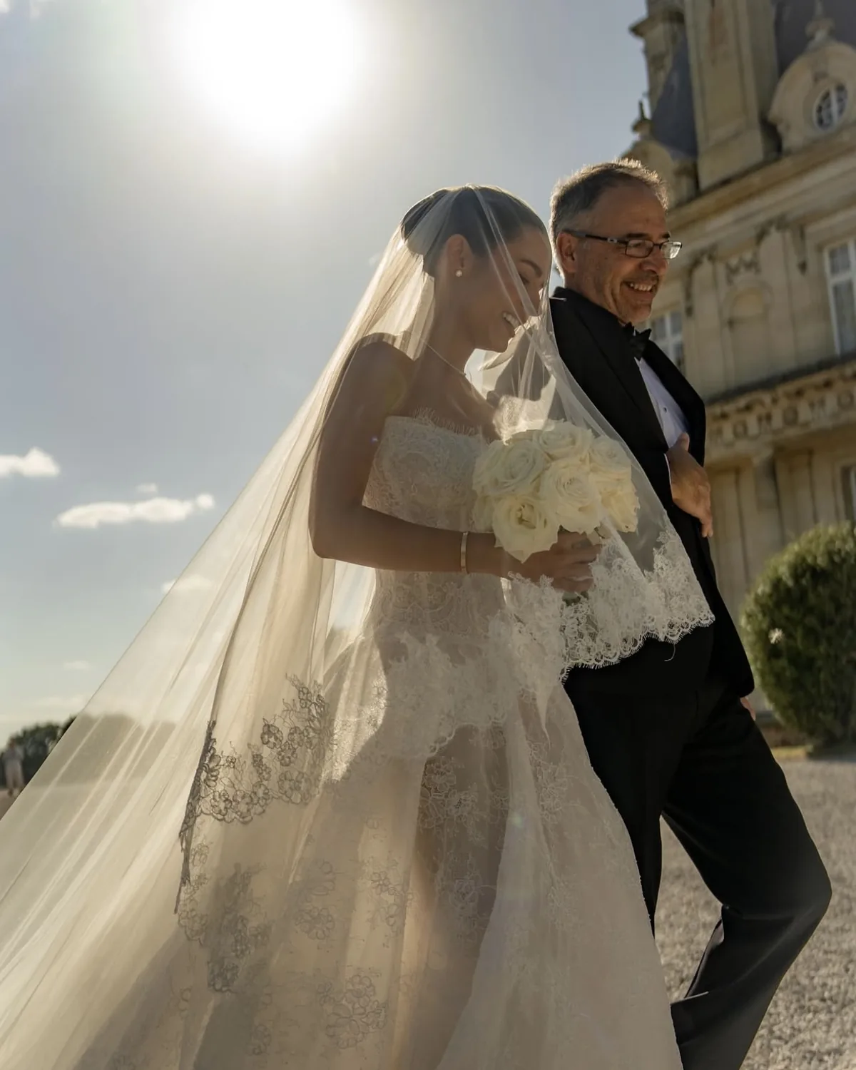 Danielle walking down the aisle in her Whisper ball gown, veil lit by afternoon sun
