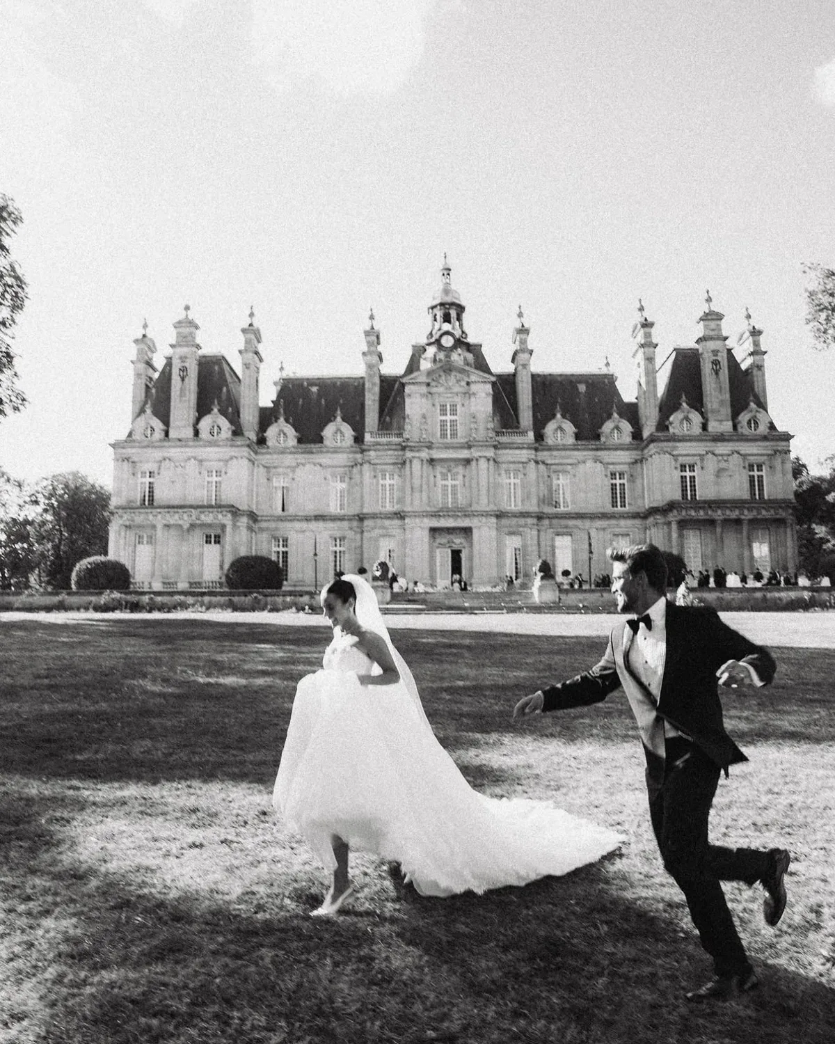 Danielle and Spencer running across the lawn in front of the château