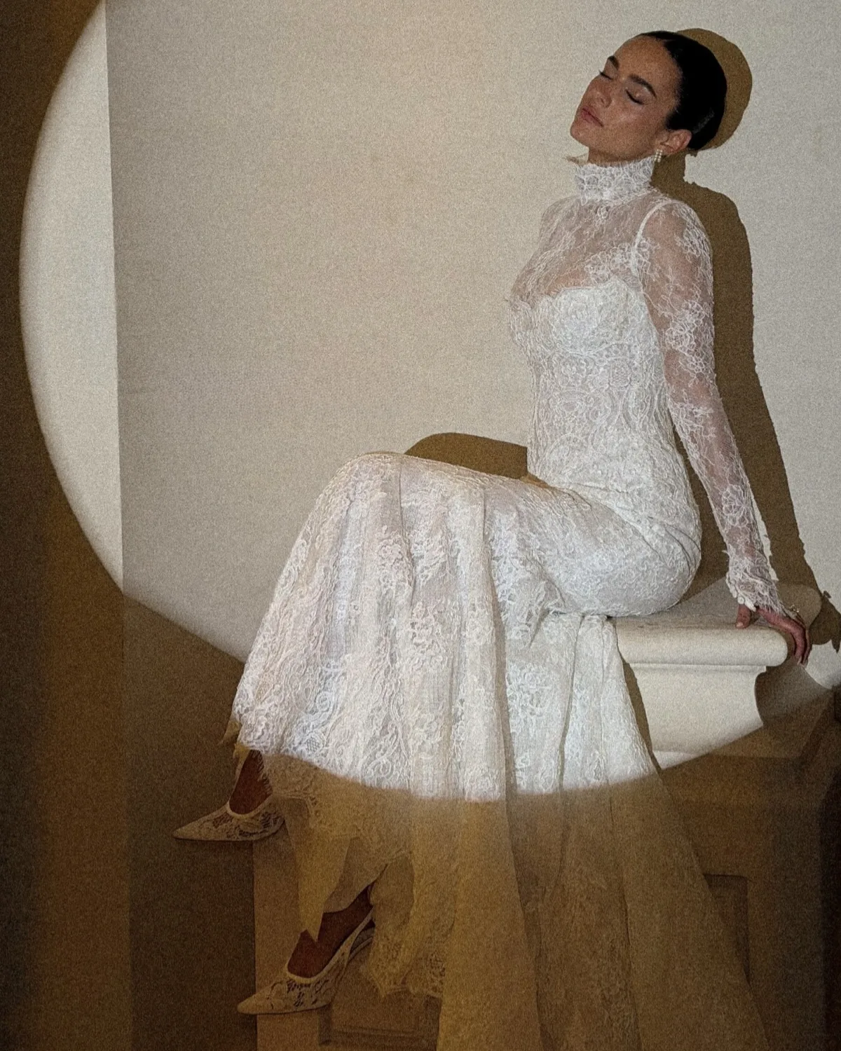 Danielle seated in her Tosca gown, the long-sleeve lace lit by afternoon light