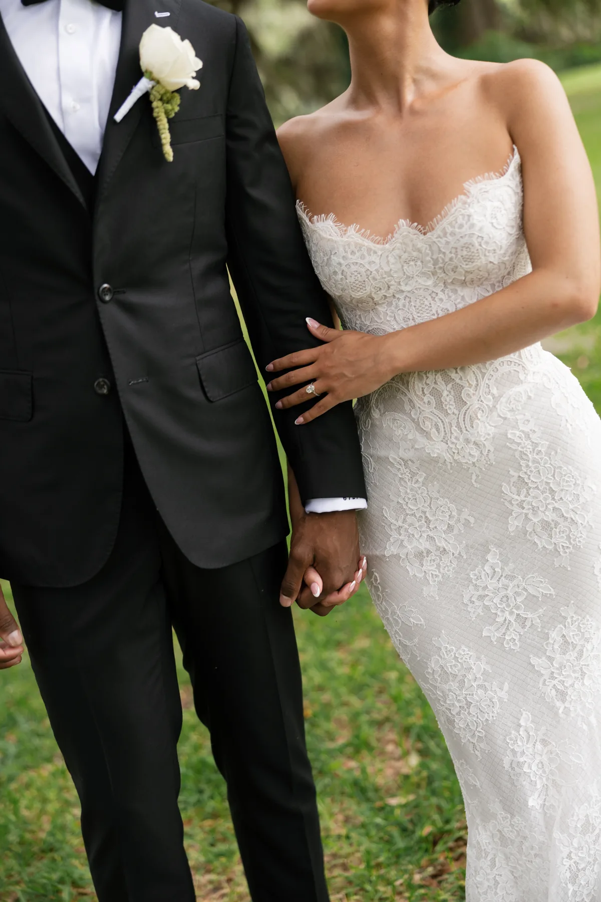 Madison and Jaylin hand in hand, his boutonniere against the lace bodice of her gown