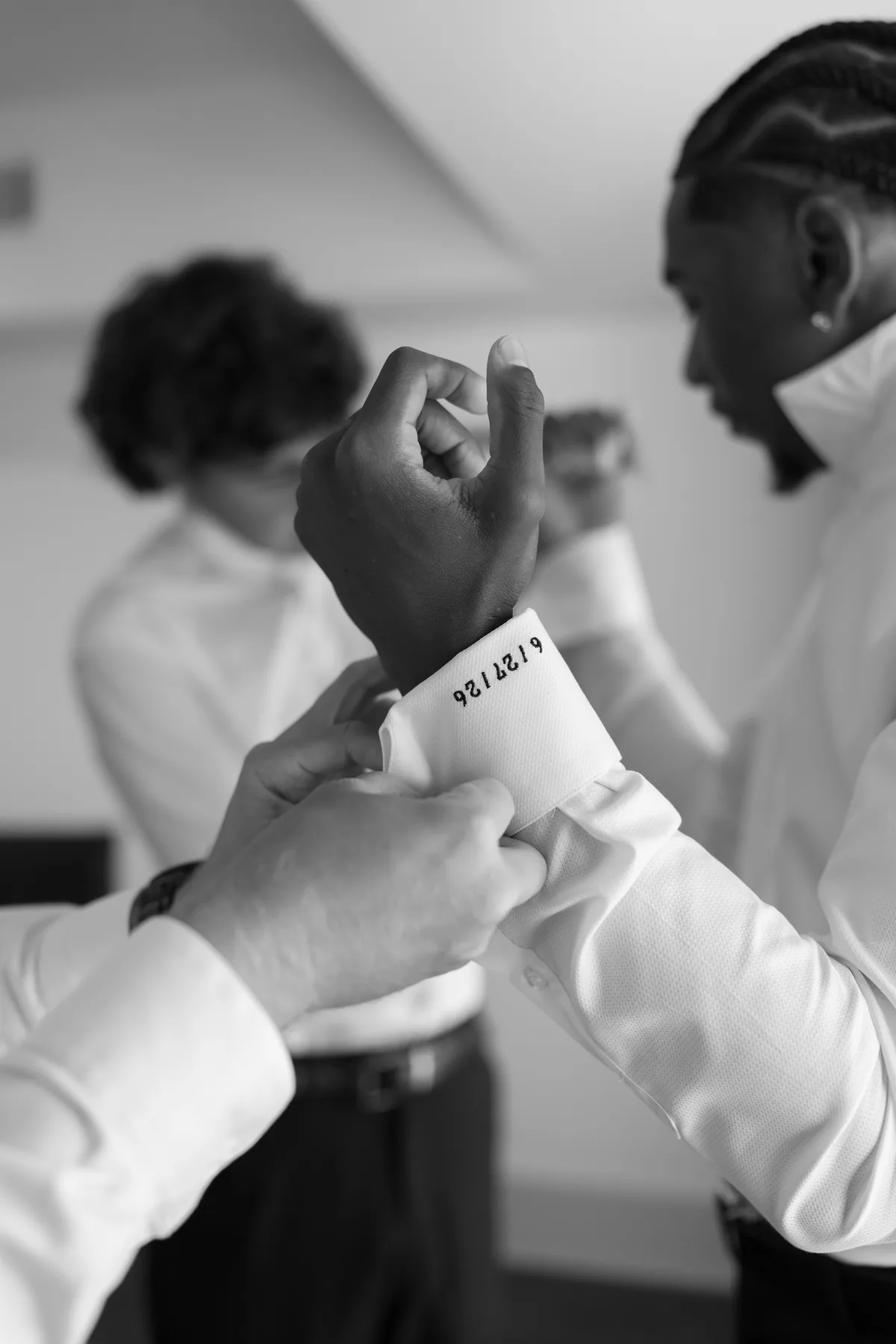 Black and white detail of cufflinks being fastened before the ceremony